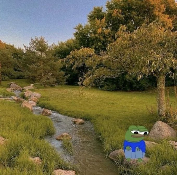 A serene landscape painting depicting a stream winding through grassy banks lined with rocks and lush trees, featuring a small, stylized green frog character wearing a blue shirt and jeans in the foreground.