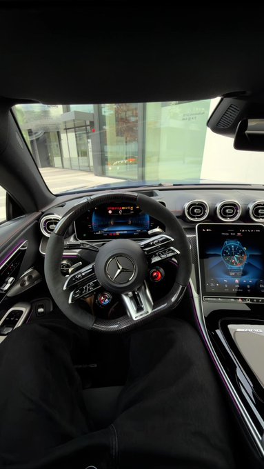 A sleek Mercedes-AMG interior is shown from the driver's seat, featuring a digital dashboard with the iconic Mercedes steering wheel and a vertical infotainment screen displaying an "AMG" logo. The caption "Good Morning CT gM if you gM" appears to be a morning greeting from the owner showcasing their luxury car.