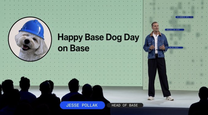 Jesse Pollak, Head of Base, presents on stage with a slide reading 'Happy Base Dog Day on Base' alongside an image of a fluffy white dog wearing a blue hard hat.
