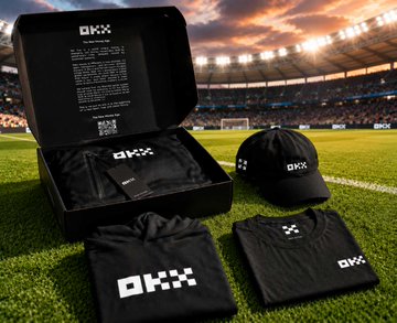 A merchandise set branded 'OKX' is displayed on a football pitch, including an open black box, a cap, a folded shirt, and a t-shirt.