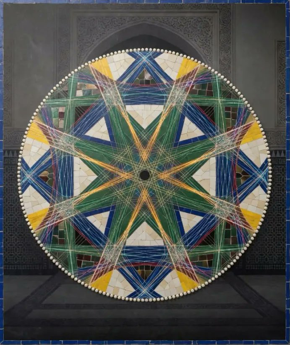 The image features an intricate mosaic artwork that is circular in shape with a star pattern at its center. The artwork is composed of small tiles arranged in a way that creates a visually appealing design. The colors used for the tiles are predominantly blue, green, yellow, and white, which contribute to the overall aesthetic appeal of the piece. The image also includes text that reads "Giving Away 1x GTD & 3x FCFS Spots @ZelijOrigins Zelij is an ancient North African and Moorish art form that has decorated palaces, mosques, fountains, and madrasas for centuries". This information suggests that the artwork may be part of a collection or exhibition showcasing the history and cultural significance of mosaic art.