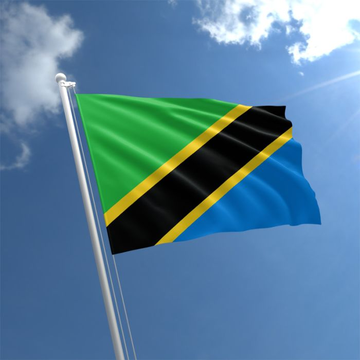 The image shows the flag of Tanzania—featuring a green, yellow, black, and blue design—waving against a bright blue sky, visually representing the country preparing new cryptocurrency and stablecoin regulations.