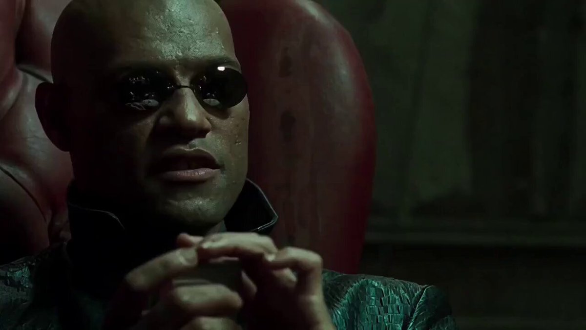 The image features an actor wearing sunglasses and a leather jacket sitting in a chair with his hands together. The background of the image shows a dark room or a dimly lit area, which adds to the overall atmosphere of the scene. There are no texts present in the image, but there is a caption that reads "Mission complete. Here' s all of my entries, fam! Shoutout to the team @taunt_bet for putting together such a wonderful and fun campaign and to everyone in the community who' s been spreading the word!".