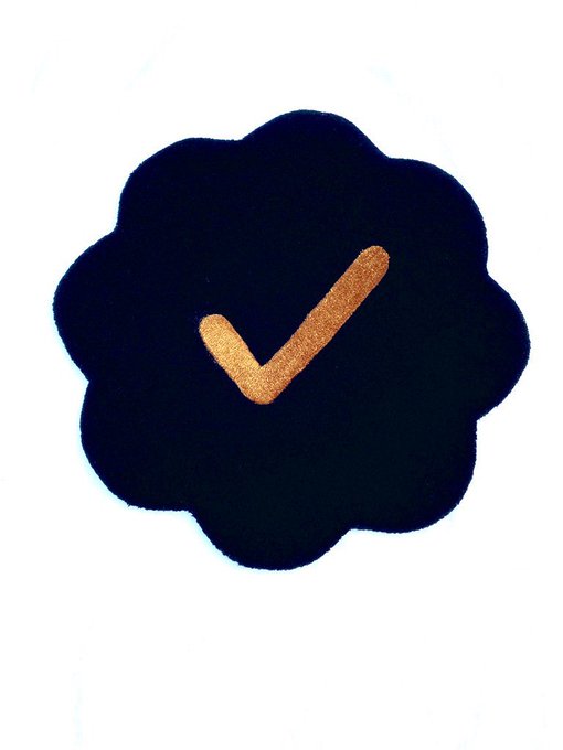 A dark scalloped badge icon featuring a gold checkmark in the center.