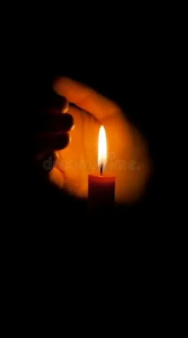 A dark, moody photograph of a hand cupped around a lit candle flame, with a 'dreamstime' watermark visible across the center of the image.