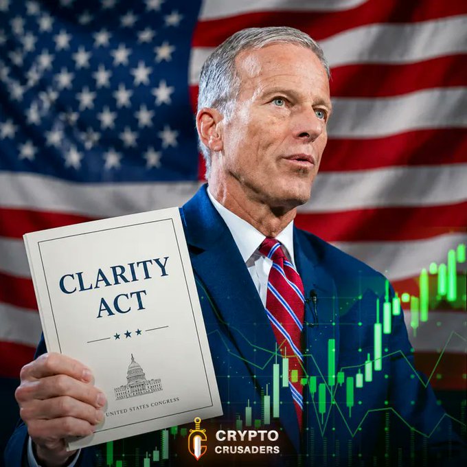 A man in a dark suit and red striped tie holds a document labeled "CLARITY ACT" featuring the U.S. Capitol building and "United States Congress," standing before an American flag backdrop with green crypto candlestick charts overlaid. The Crypto Crusaders logo appears at the bottom, visually reinforcing the post's bullish sentiment about Senate Republican Leader Thune's push to advance the Clarity Act legislation, which the post cites as positive for crypto and XRP.
