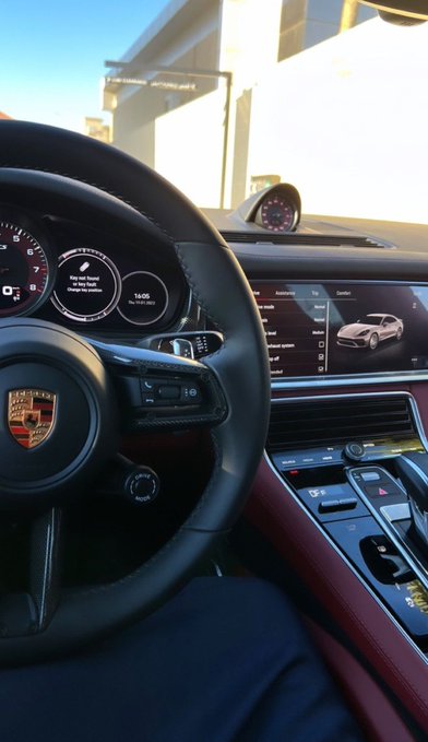 The image shows the interior of a Porsche, with the steering wheel's iconic crest, digital dashboard displaying "14:05" and a message prompting to "Set Key Now!", and the center console showing a 3D model of a Porsche Panamera. This luxury setting ties into the post's "GOOD MORNING" greeting, suggesting the poster is enjoying a stylish morning drive while inviting others to drop their Solana (SOL) cryptocurrency address.