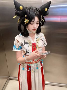 A young woman wearing an ornate headdress with large black horn-like decorations and a traditional white and red embroidered outfit stands in an elevator, looking down at her smartphone. The caption "So pretty, it's my type. Let's add each other on WeChat." complements the image, suggesting the poster admires her traditional attire and is initiating a friendly connection.