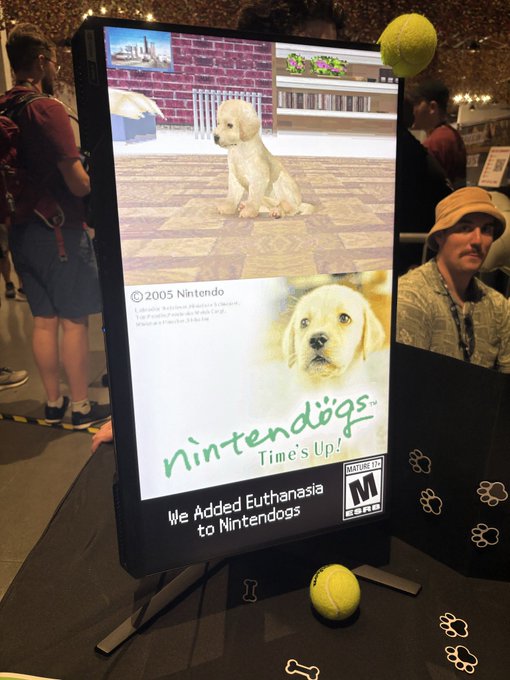 The image shows a parody "Nintendogs" game box at what appears to be a gaming convention, displaying a cute golden retriever puppy on the cover with the tagline "We Added Euthanasia to Nintendogs" and a "M" for Mature rating. The humorous, subversive take on a beloved Nintendo title perfectly illustrates the post's theme of "innovation happening"—showcasing how creators are reimagining familiar franchises through darkly comedic reinterpretations.