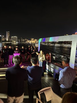 A nighttime event shows people gathered on an outdoor terrace overlooking a city skyline and water, with a large screen displaying content in the background. The setting reflects the post's commentary on Solana establishing a visible presence and office in China, contrasting this with BNBChain's apparent inability to do the same.
