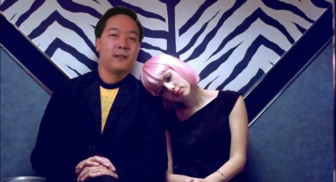 A man in a black blazer poses alongside a woman wearing a bright pink wig, seated in front of a striking zebra-print backdrop with bold geometric lines. The playful, eclectic styling and casual posing playfully echo the post's lighthearted message that "Nothing is Lost In Transaction with Litecoin," suggesting cryptocurrency's seamless and stylish reliability.