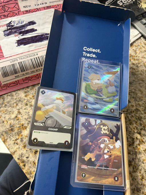 Three holographic trading cards including 'CHAMP' (green Common card) and pirate-themed cards 'BARTON' and 'RENZA' displayed in an open blue box labeled 'Collect. Trade. Repeat.'