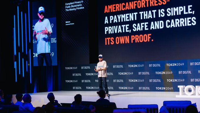 Speaker presenting on stage at TOKEN 2049 / BIT DIGITAL conference promoting 'AmericanFortress' as 'a payment that is simple, private, safe and carries its own proof,' positioned as compliant privacy in public blockchains.