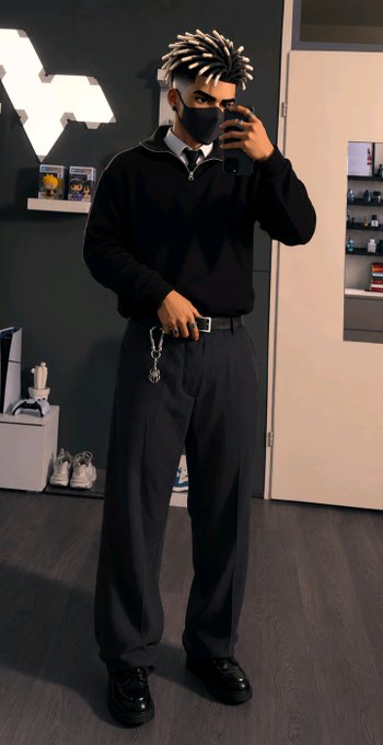 A mirror selfie shows a person with dreadlocks wearing a black face mask, black sweater, tie, and black wide-leg trousers, with a chain accessory hanging from the belt.
