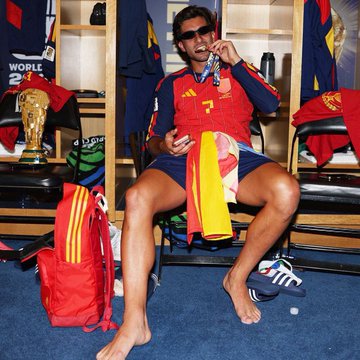 A Spain soccer player wearing a red #7 jersey sits in the locker room barefoot with a trophy visible in the background, likely after the World Cup final. The image ties to the post's reference to Stake's "Finale" promotion, humorously suggesting the betting platform's finale outdid the actual Argentina vs Spain match in entertainment value.