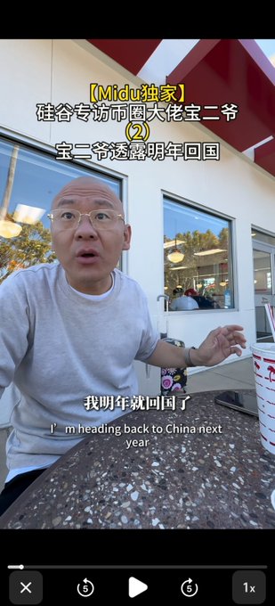 A video still featuring a bald man with glasses at a restaurant, with Chinese subtitles indicating a statement "I'm heading back to China next year," labeled as an exclusive Midu Silicon Valley interview with "Bao Er Ye."