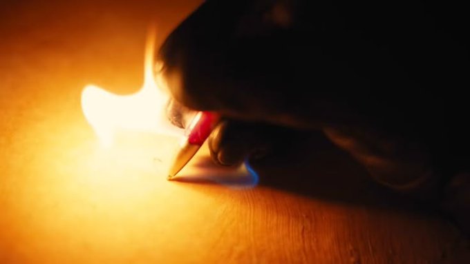 A hand lifts a flame from a small square piece of paper, the fire glowing warmly in the dark as the paper begins to burn. The image visually echoes the caption's bold sentiment, suggesting ambitions too great for any boundary—even the earth itself—to contain.