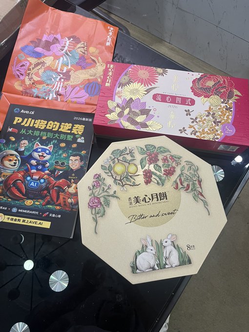 A collection of mooncake boxes and packaging, including designs with Chinese text '美心月餅' and 'P小將的逆襲', are arranged on a glass table.