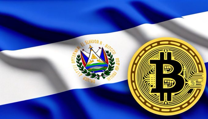 The waving flag of El Salvador is displayed alongside a large golden Bitcoin coin against a dark background, referencing the country's adoption of Bitcoin as legal tender.