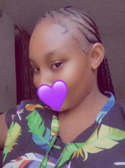 A selfie of a young person with braided hair wearing a colorful tropical-patterned shirt, with a purple heart emoji covering their mouth.