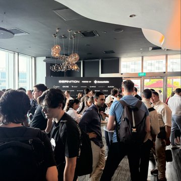 A crowded indoor event space with many attendees, decorative pendant lighting, and signage for 'REKTION' and 'CHILDCARE'.