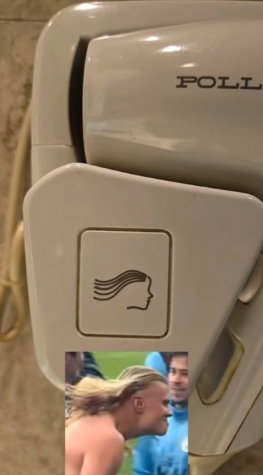 A wall-mounted Polident hand dryer with a hair-dryer icon, with a small inserted photo of a man with a distinctive mullet hairstyle in a crowd.