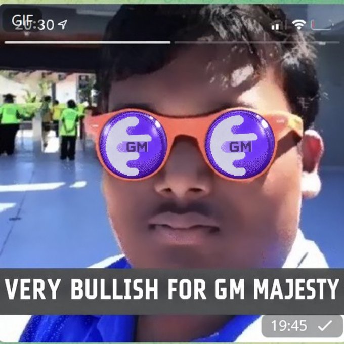 A selfie of a young man wearing sunglasses with 'GM' on the lenses, captioned 'VERY BULLISH FOR GM MAJESTY' at the bottom, showing 19:45 as the time.
