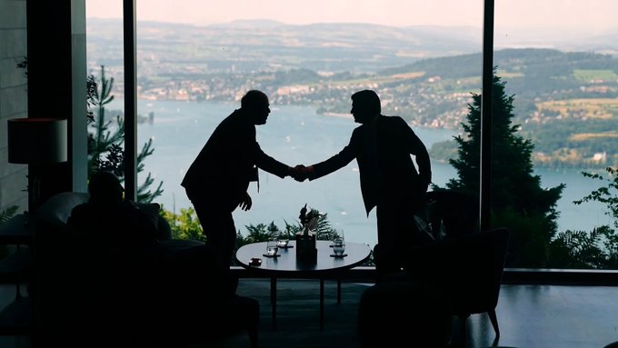 Two businessmen shake hands across a table in a high-rise office overlooking a scenic lake and mountain view. The image of a stagnant, outdated business arrangement contrasts with the post's frustration about repetitive, unchanging content that fails to deliver any new developments.