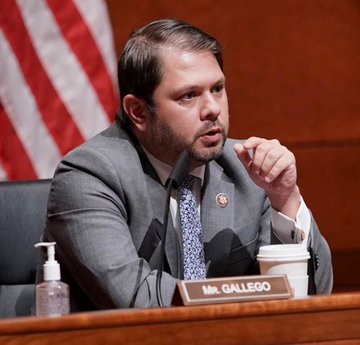 Democratic Senator Ruben Gallego speaks at a hearing, with a nameplate reading "Mr. GALLEGO" visible on the desk in front of him. The image accompanies news of his criticism of the ethics provisions in the Clarity Act and his announcement that Democrats will send a counterproposal before the bill reaches the Senate floor.