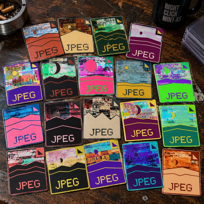 A collection of decorative cards or coasters featuring retro pixel-art landscape designs with the text 'JPEG' on them, displayed on a wooden surface.