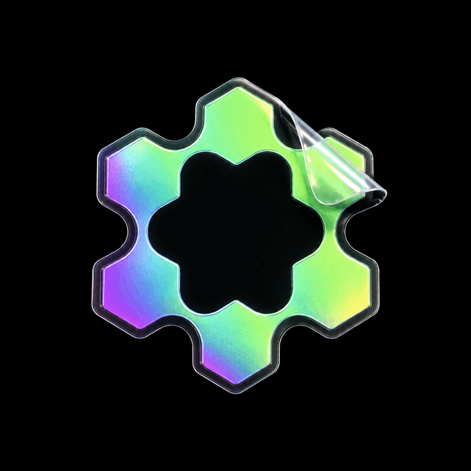 A holographic sticker with an iridescent, six-petaled flower/hexagonal shape featuring a pealing corner, set against a solid black background.