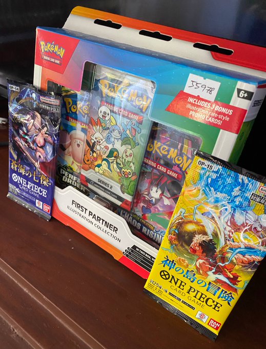 A retail display of Pokémon Trading Card Game products, including the 'First Partner Illustration Collection' priced at $59.98 featuring Charizard, alongside Japanese 'One Piece' card game booster packs.