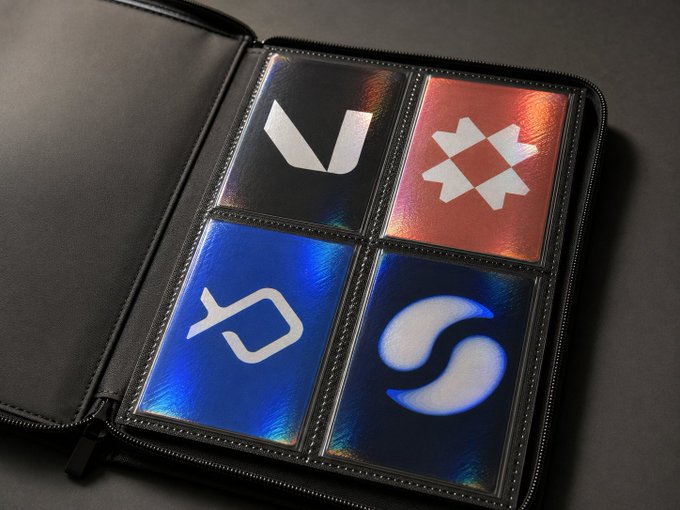 An open black zippered binder contains holographic card sleeves showing logos for V, T, and S symbols on black, red, and blue backgrounds.