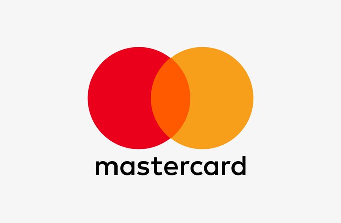 The image shows the modern Mastercard logo, featuring its iconic two overlapping circles in red and yellow-orange with the "mastercard" wordmark below, set against a light gray background. The logo relates to the post about Mastercard's reported $1.8 billion acquisition of Zerohash, illustrating the company's expanding role in the crypto payments industry.