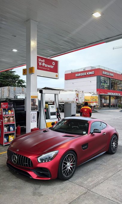 A matte red Mercedes-Benz sports car parked at a Shell V-Power gas station with a Burger King restaurant visible in the background.