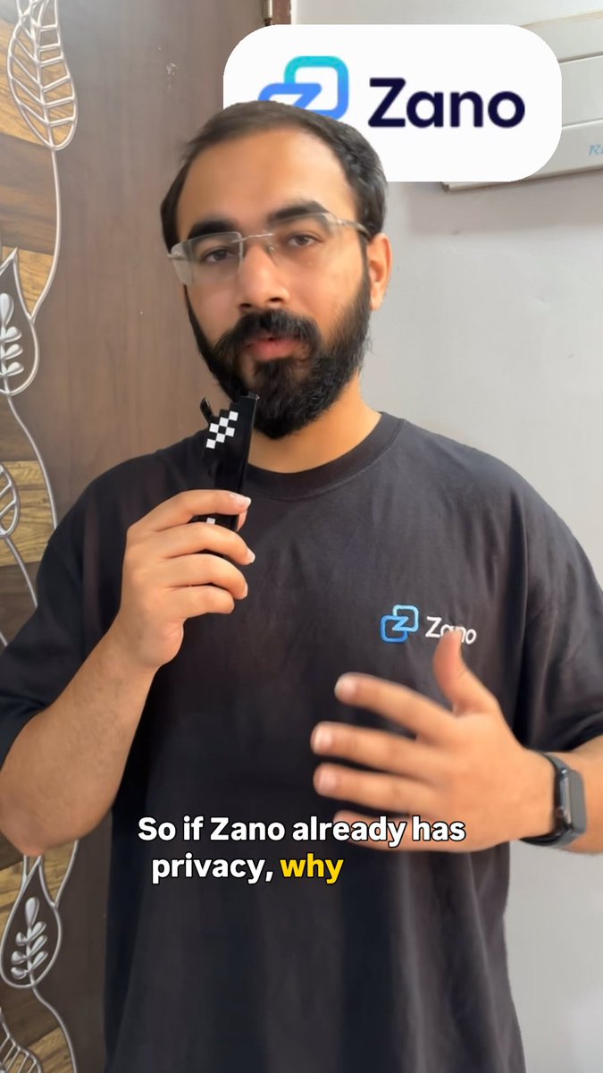A bearded man wearing glasses and a black 'Zano' branded t-shirt speaks into a microphone while a Zano logo overlay appears at the top, with on-screen text reading 'So if Zano already has privacy, why'.