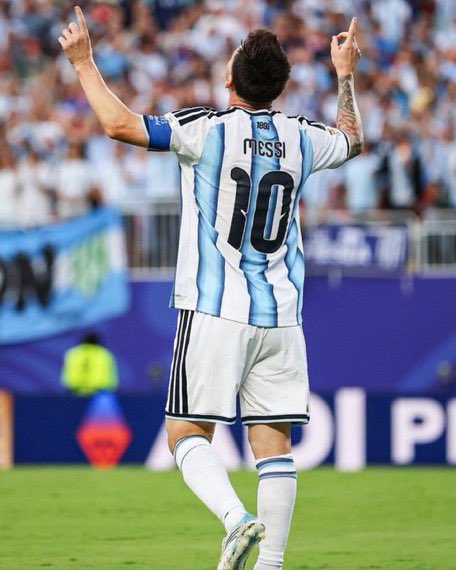 Lionel Messi, wearing the #10 Argentina jersey, celebrates with arms raised pointing skyward after scoring, fueling hopes of an Argentina World Cup victory that would make the poster's $50 promise to likers a reality.
