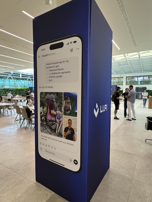 A tall blue advertising pillar in what appears to be a cafeteria or office space displays the "LI.FI" logo and a mockup of a smartphone showing a ChatGPT conversation with a LiFi Inherits ad.