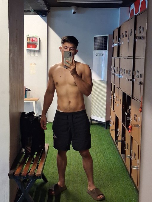 A shirtless young man takes a mirror selfie in what appears to be a gym locker room, showcasing his lean physique as he poses in black shorts and sandals. The caption "Medjo pump na for weekend" suggests he's sharing a post-workout flex, highlighting the muscle definition he achieved before the weekend.