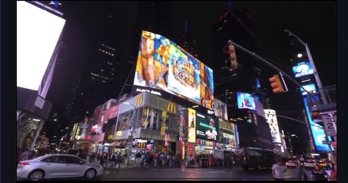 A father-daughter artist duo (@alperozdilart) sees their colorful artwork displayed on a massive NYC Times Square billboard at night, surrounded by the iconic glow of McDonald's golden arches, Nasdaq, and other bright advertisements as crowds gather below to witness the moment marking their Times Square debut after four years.