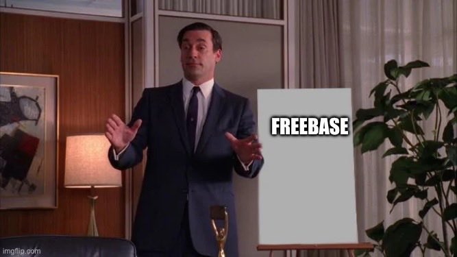 A meme featuring Don Draper gesturing toward a blank sign labeled 'FREEBASE' next to a golden trophy.
