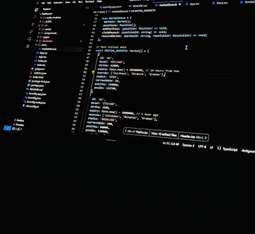 A computer monitor displays VS Code with code in a file named "main.zig", likely using the Zig programming language. The visible code includes imports like `std.debug`, `std.heap`, and `std.testing`, along with custom struct definitions like `BetInfo` and `Market`, suggesting the user is building a project related to prediction markets or betting platforms. This aligns with the post's teasing of an upcoming project, with the code hinting at development involving Base, RialoHQ, Arc, or Polymarket.