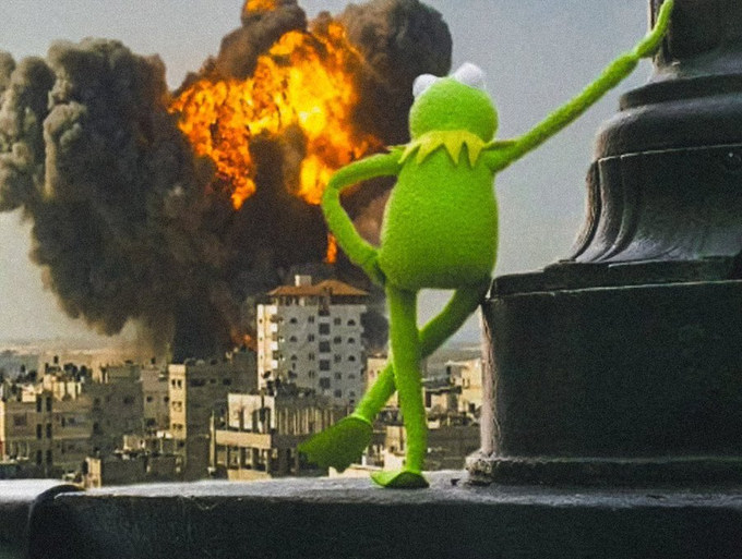 Kermit the Frog stands calmly with his back to the viewer, looking out over a cityscape with a massive explosion erupting in the background.