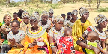 A group of women and children in traditional African attire, featuring colorful beaded jewelry and headwraps, sit together outdoors in what appears to be a community gathering. The image accompanies a post titled "XRP Family," likely drawing a metaphorical parallel between the strong, united community depicted and the supportive community within the XRP cryptocurrency ecosystem.