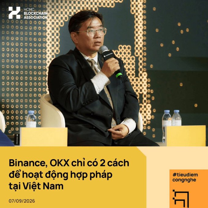 A man in a suit speaks into a microphone at an HCMC Blockchain Association event, with text reading 'Binance, OKX chỉ có 2 cách để hoạt động hợp pháp tại Việt Nam' dated 07/09/2026.