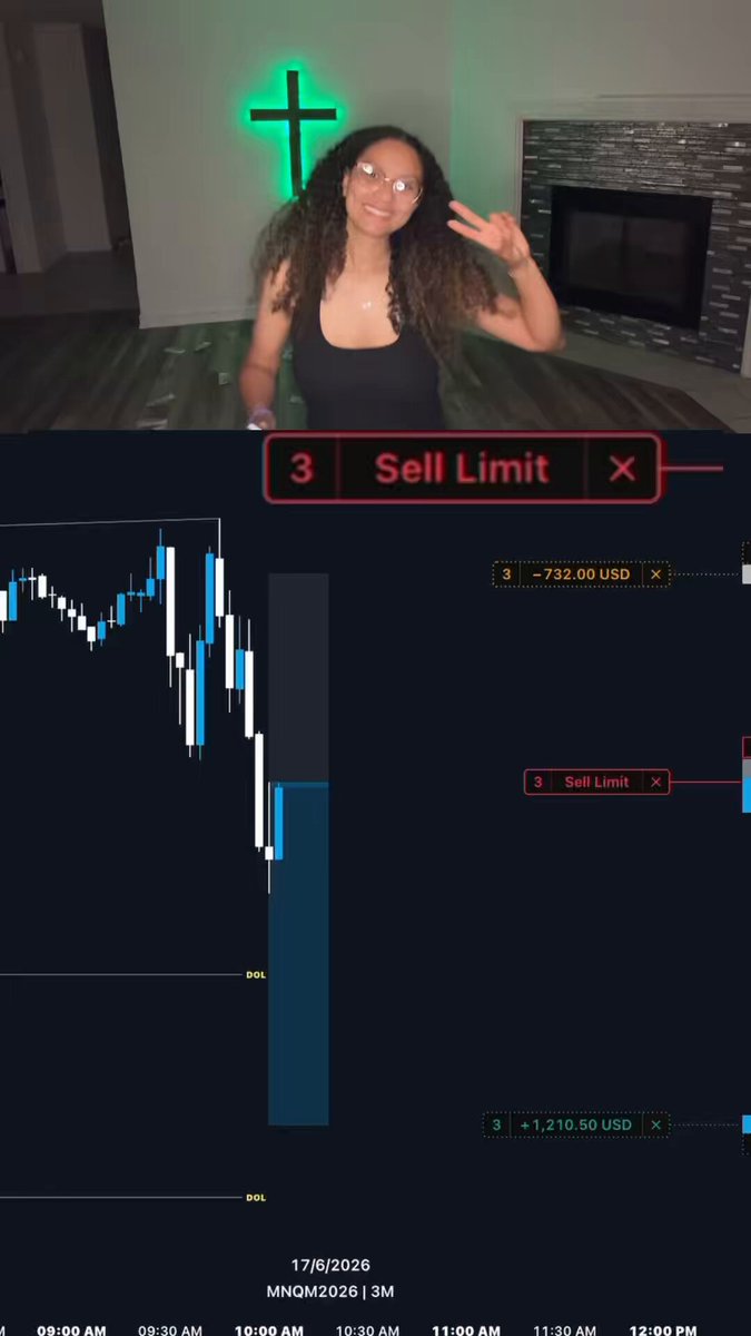 The image shows a woman posing for a picture with her hand raised, wearing a black tank top. She has curly hair that she is holding back from falling into her face as she poses. The background of the photo features a fireplace and a green neon sign in the corner. There are also some numbers on the screen behind the woman, which could be related to the stock market or financial data.