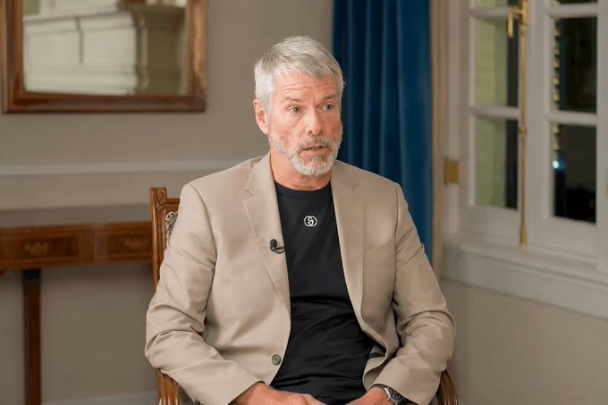 The image shows Michael Saylor, executive chairman of Strategy (formerly MicroStrategy), sitting in a tan blazer during what appears to be an interview. The caption relates to the post discussing Strategy's cash reserve growth to $3.75 billion through a recent share sale, with Saylor mentioned in the accompanying text commenting on the company's financial position.