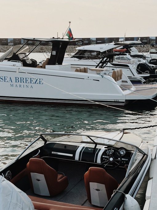 Luxury yachts docked at Sea Breeze Marina, with a smaller speedboat featuring brown leather seats in the foreground.
