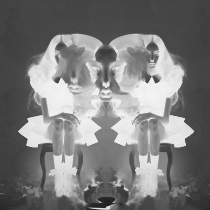 A black-and-white mirrored/symmetrical surreal image showing a seated figure in a tutu with ghostly faces and floral elements bleeding into the composition.