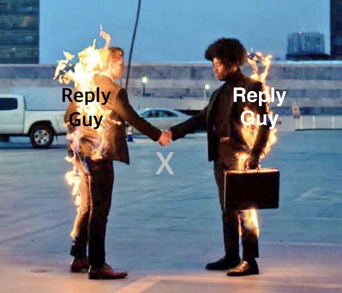 The image shows two men in suits on fire, shaking hands on a rooftop parking lot, with text labeling them as "Reply Guy" on each side, separated by an "X" — humorously depicting the endless cycle of "reply guys" on social media, where users are asked to type "Yes" to engage and boost their numbers, referencing the "watch your numbers grow" follow culture.